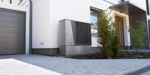 Unidad exterior de bomba de calor aerotérmica junto a una vivienda