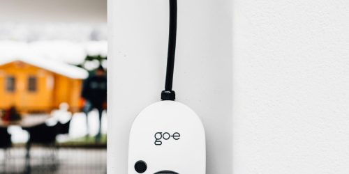 Vehículo eléctrico conectado a un punto de recarga en un aparcamiento